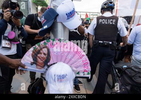 Chicago, Illinois, USA. August 2024. Ein Mann, der Kamala Harris-Waren verkauft, zeigt einen Fan, während Polizei und Demonstranten gegen die Demokratische Nationalversammlung in Chicago marschieren. (Kreditbild: © J. Daniel HUD/ZUMA Press Wire) NUR REDAKTIONELLE VERWENDUNG! Nicht für kommerzielle ZWECKE! Stockfoto