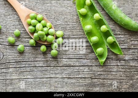 Frische grüne Erbsen mit Schote auf hölzernem Hintergrund, gesundes grünes Gemüse oder Hülsenfrüchte ( pisum sativum ) Stockfoto