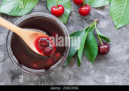 Sauerkirschmarmelade im Glas oder in einer Schüssel mit frischen, rohen Sauerkirschen Stockfoto
