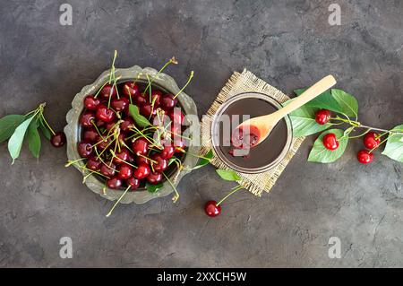 Sauerkirschmarmelade im Glas oder in einer Schüssel mit frischen, rohen Sauerkirschen Stockfoto