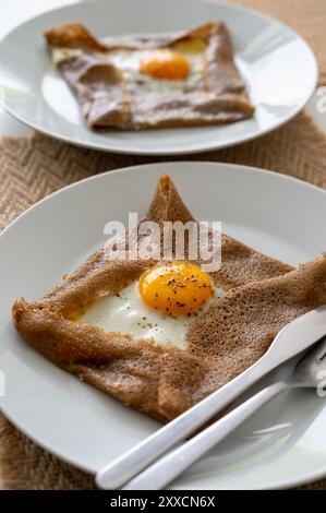 Galettes-Pfannkuchen aus der Bretagne mit Buchweizenmehl, serviert mit herzhaften Toppings, Schmelzkäse und Eiern aus nächster Nähe Stockfoto