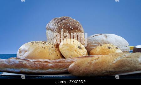 Verschiedene Brotsorten in einem rustikalen Korb, isoliert auf blauem Hintergrund. Französisches Brot . Hausgemachtes Brot im ländlichen Sibt. Hausgemachtes Gebäck Stockfoto
