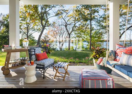 Veranda mit Blick auf den See mit einer Veranda Schaukel und Stuhl und Getränkekarren Stockfoto