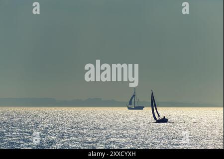 Eine moderne Segelyacht und ein historisches Zahnrad vor dem Licht der Ostsee Stockfoto