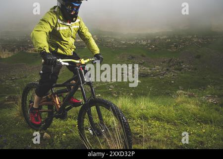 Ein Mann in einem Berghelm mit dem Mountainbike fährt um die schöne Natur bei bewölktem Wetter. Bergab Stockfoto