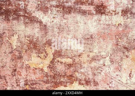 Rosa-rot strukturierter Hintergrund aus mehrschichtiger abblätternder Farbe an der Wand. Mischen verschiedener Farben von Farben in den aufgespaltenen Schichten auf der Oberfläche. Grunge Stockfoto