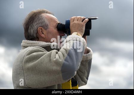 Mann in Seitenansicht, der durch ein Fernglas schaut Stockfoto