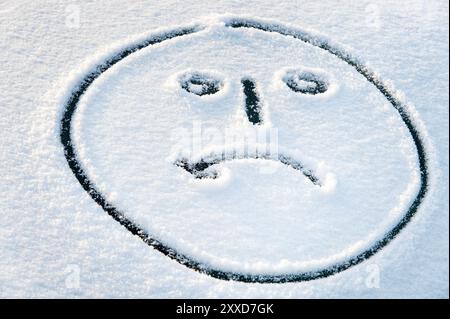 Weinendes Gesicht auf der schneebedeckten Windschutzscheibe eines Autos Stockfoto