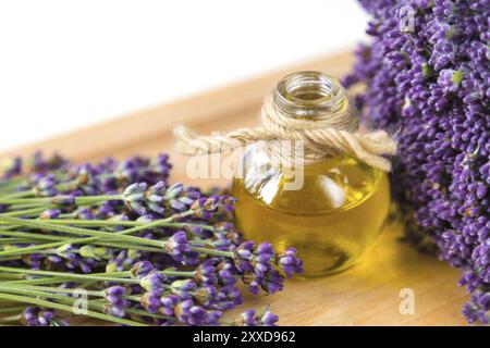 Frische Lavendelblüten und eine Flasche Öl auf Holz- Hintergrund Stockfoto