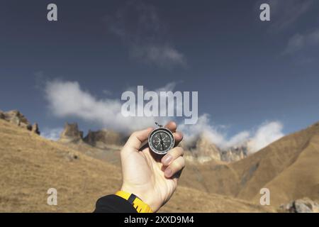 Ein männlicher Wanderer sucht im Herbst eine Richtung mit einem magnetischen Kompass in den Bergen. POV-Aufnahme. Die Hand eines Mannes mit einem Uhrenarmband Stockfoto