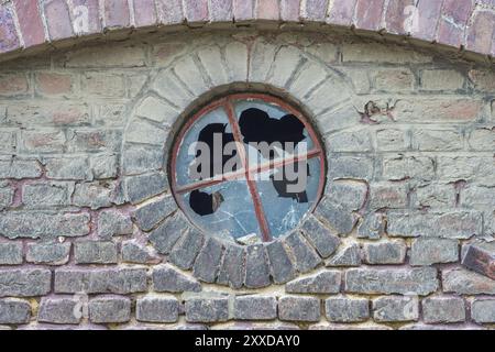 Rundes Fenster mit kaputten Scheiben auf einer alten Scheune Stockfoto