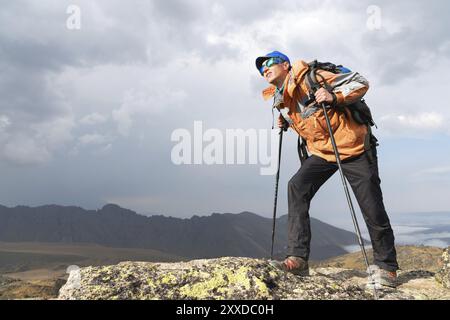 Ein Porträt einsamer Tourist mit Rucksack und Sonnenbrille genießt die Aussicht hoch in den Bergen des Kaukasus, wo es kein Gras gibt, die V Stockfoto