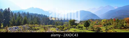 Das farbenfrohe Herbstpanorama von Pirin, Bulgarien, mit farbenfrohen grünen, roten und gelben Bäumen und Berggipfeln Stockfoto