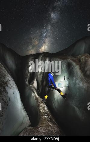 Nächtliche Landschaft des Gletschers. Klettermännchen in einer Spalte mit Eisäxten und einer leeren Flagge in den Händen steht wieder auf einer Insel zwischen den Eiswänden Stockfoto