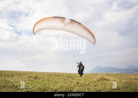 Der Gleitschirmflieger öffnet seinen Fallschirm, bevor er vom Berg im Nordkaukasus abhebt. Füllen Sie den Fallschirmflügel vor dem Start mit Luft Stockfoto