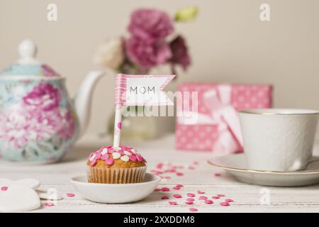 Köstlicher Kuchen mit dekorativer Flagge mit Mama-Titel in der Nähe von Teekannen Tasse Stockfoto