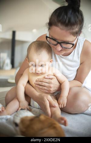 Mutter, die Baby hält, wackelt Beagle und schläft. Baby mit Hundespiele Stockfoto