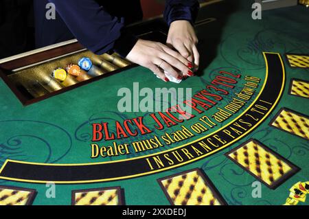 Hände eines Croupier-Händlers an einem Blackjack-Kartentisch, der die Karten in einem Casino mischt Stockfoto