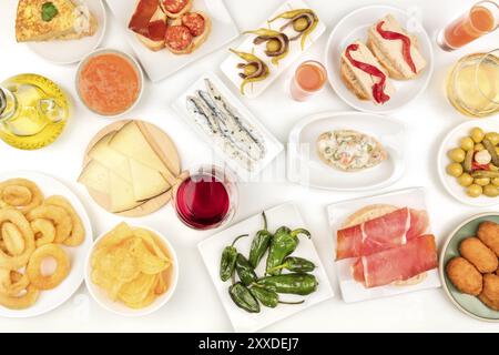 Spanische Tapas und Wein, ein Foto von einer Auswahl an Snacks über dem Kopf. Gazpacho, Tintenfischringe, Tortilla, Marmelade, Käse usw. von oben auf weißem Hintergrund geschossen Stockfoto