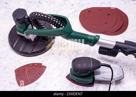 Wandschleifer mit Teleskopgriff, Detailschleifer und Schleifpapier zum Glätten und Schleifen von Wänden auf grauweißem Hintergrund. Stockfoto