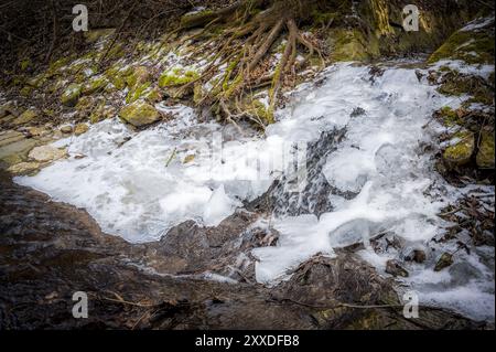 Kleiner Bach und Wasserfall im Winter mit Eis Stockfoto