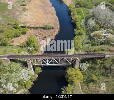 Aus der Vogelperspektive auf die Eisenbahnbrücke über einen kleinen Fluss Stockfoto
