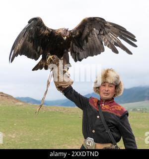 Issyk Kul, Kirgisistan – 23. Mai 2022: Adlertrainer mit seinem goldenen Adler, der traditionelle Jagdtechniken zeigt, die über Generationen weitergegeben wurden. Stockfoto