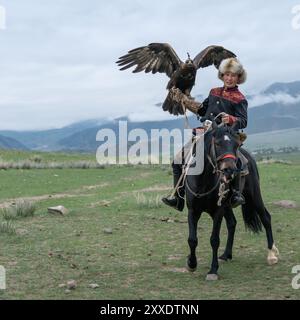 Issyk Kul, Kirgisistan - 23. Mai 2022: Adlertrainer zu Pferd mit seinem goldenen Adler, der traditionelle Jagdtechniken zeigt, die durch g übertragen wurden Stockfoto