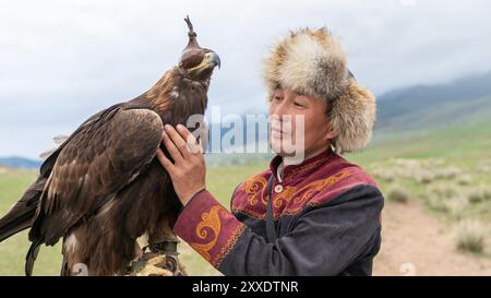 Issyk Kul, Kirgisistan – 23. Mai 2022: Adlertrainer mit seinem goldenen Adler, der traditionelle Jagdtechniken zeigt, die über Generationen weitergegeben wurden. Stockfoto