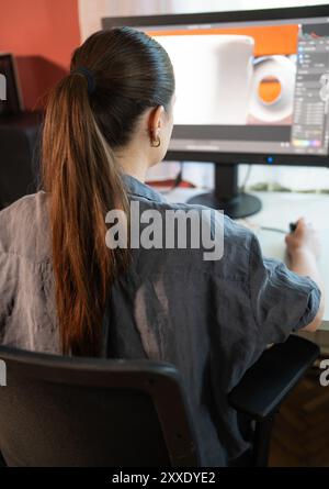 Eine junge Frau sitzt an einem Computer im Büro und macht Grafikdesign Stockfoto