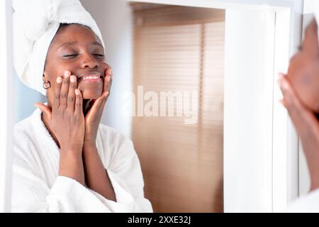 Glückliche schwarze Frau mit Gesichtspflegeprodukten. Hautpflege, Gesichts- und kosmetische Morgenselbstpflege. Stockfoto
