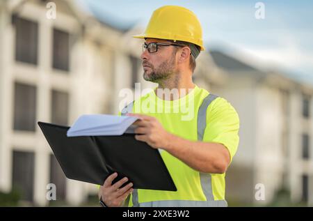 Ingenieur mit Klemmbrett, Gebäudeinspektion. Bauarbeiter vor Ort. Arbeiter mit Schutzhelm. Bauarbeiter im Helm bei Neubau Stockfoto