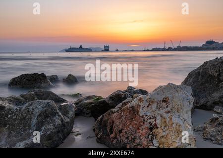 Sonnenuntergang am Strand in der Nähe der Stadt Vlorë in Albanien, die sich an der Bucht von Vlorë ausbreitet und von den Ausläufern der Ceraunischen Berge Ao umgeben ist Stockfoto