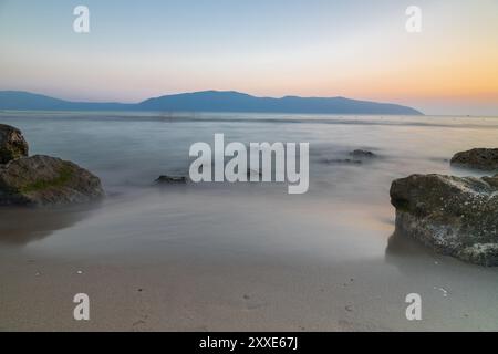 Sonnenuntergang am Strand in der Nähe der Stadt Vlorë in Albanien, die sich an der Bucht von Vlorë ausbreitet und von den Ausläufern der Ceraunischen Berge Ao umgeben ist Stockfoto