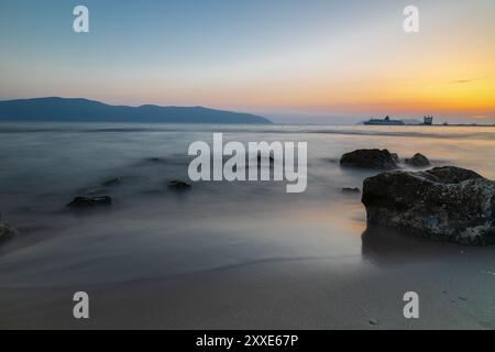 Sonnenuntergang am Strand in der Nähe der Stadt Vlorë in Albanien, die sich an der Bucht von Vlorë ausbreitet und von den Ausläufern der Ceraunischen Berge Ao umgeben ist Stockfoto