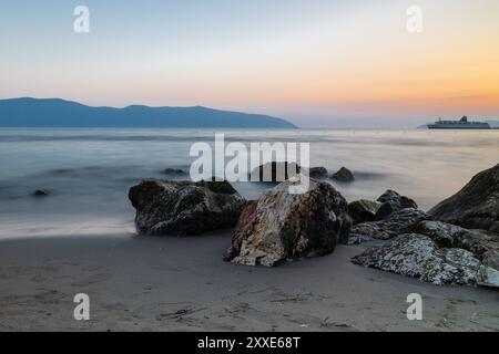 Sonnenuntergang am Strand in der Nähe der Stadt Vlorë in Albanien, die sich an der Bucht von Vlorë ausbreitet und von den Ausläufern der Ceraunischen Berge Ao umgeben ist Stockfoto