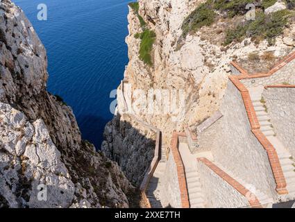 Blick von der Spitze der steilen Treppe zwischen den steilen Klippen, die zur Grotte von Neptun mit dem blauen Meer im Hintergrund in der Nähe von Alghero auf der i führen Stockfoto