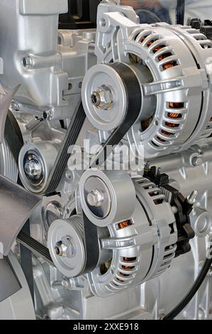 Moderner Verbrennungsmotor, Nahaufnahme. Sichtbare äußere Teile – Generator, Antriebsriemen, Riemenscheiben und Leiträder Stockfoto