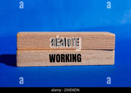 Meldung über die Fernbedienung auf Holzblöcken mit blauem Hintergrund. Konzeptionelles Symbol für Remote Working. Kopierbereich. Stockfoto