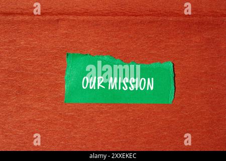 Unsere Botschaft auf gerissenem grünem Papier mit braunem Hintergrund. Konzeptionelles unser Missionssymbol. Kopierbereich. Stockfoto