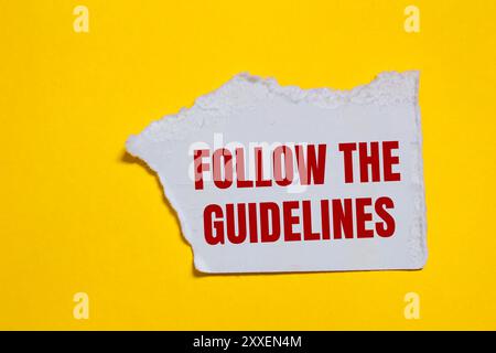 Befolgen Sie die Anweisungen auf einem gerissenen weißen Papierstück mit gelbem Hintergrund. Konzeptionell Befolgen Sie das Richtliniensymbol. Kopierbereich. Stockfoto