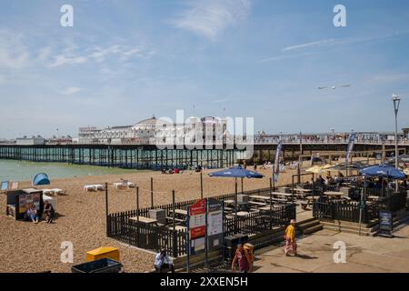 Eine Landschaftsansicht des Brighton Pier von der linken Seite des Piers mit Strand und Café im Vordergrund. Stockfoto