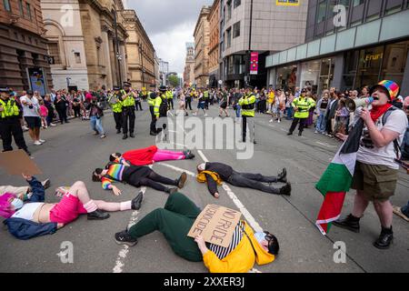 Manchester, Großbritannien. August 2024. Palästinensische Gaza-Kriegsproteste liegen vor der Pride Parade auf der Straße. Die palästinensischen Demonstranten konnten die Pride Parade nicht verhindern, nachdem sie die Straße auf der Peter Street blockierten. Sie protestierten gegen Booking.com, die auch Werbung für Immobilien in Israel führen. Die Polizei ging ein und genehmigte den Protest, damit der Protest fortgesetzt werden konnte. Einige Personen in der Parade trugen palästinensische Fahnen. Manchester Pride 2024 . Das diesjährige Thema lautet "Buzzin to be Queer - A Hive of Progress". Das Symbol der Manchester Bee führte die Parade an. Gutschrift Stockfoto