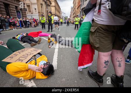 Manchester, Großbritannien. August 2024. Palästinensische Gaza-Kriegsproteste liegen vor der Pride Parade auf der Straße. Die palästinensischen Demonstranten konnten die Pride Parade nicht verhindern, nachdem sie die Straße auf der Peter Street blockierten. Sie protestierten gegen Booking.com, die auch Werbung für Immobilien in Israel führen. Die Polizei ging ein und genehmigte den Protest, damit der Protest fortgesetzt werden konnte. Einige Personen in der Parade trugen palästinensische Fahnen. Manchester Pride 2024 . Das diesjährige Thema lautet "Buzzin to be Queer - A Hive of Progress". Das Symbol der Manchester Bee führte die Parade an. Gutschrift Stockfoto