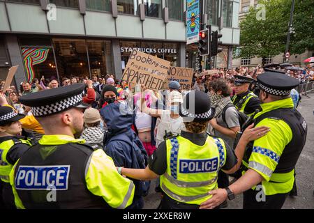 Manchester, Großbritannien. August 2024. Demonstranten des palästinensischen Krieges werden vor der Manchester Pride Parade von der Polizei in der Peters Street freigelassen. Die palästinensischen Demonstranten konnten die Pride Parade nicht verhindern, nachdem sie die Straße auf der Peter Street blockierten. Sie protestierten gegen Booking.com, die auch Werbung für Immobilien in Israel führen. Die Polizei ging ein und genehmigte den Protest, damit der Protest fortgesetzt werden konnte. Einige Personen in der Parade trugen palästinensische Fahnen. Manchester Pride 2024 . Das diesjährige Thema lautet "Buzzin to be Queer - A Hive of Progress". Das Symbol der Manchest Stockfoto