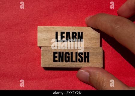 Lernen Sie englische Botschaft auf Holzblöcken mit rotem Hintergrund. Symbol für konzeptuelles Lernen englisch. Kopierbereich. Stockfoto