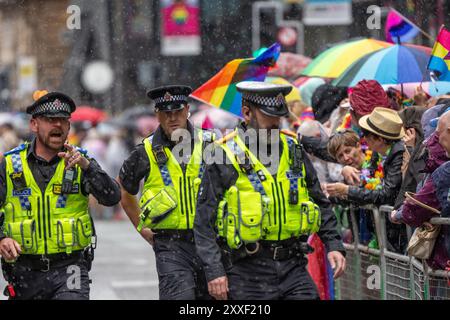 Manchester, Großbritannien. August 2024. Bei der Manchester Pride Parade fällt Regen auf Polizei und Öffentlichkeit. Die palästinensischen Demonstranten konnten die Pride Parade nicht verhindern, nachdem sie die Straße auf der Peter Street blockierten. Sie protestierten gegen Booking.com, die auch Werbung für Immobilien in Israel führen. Die Polizei ging ein und genehmigte den Protest, damit der Protest fortgesetzt werden konnte. Einige Personen in der Parade trugen palästinensische Fahnen. Manchester Pride 2024 . Das diesjährige Thema lautet "Buzzin to be Queer - A Hive of Progress". Das Symbol der Manchester Bee führte die Parade an. Gutschrift: Ga Stockfoto