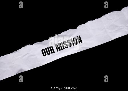 Unsere Botschaft auf gerissenem weißem Papier mit schwarzem Hintergrund. Konzeptionelles unser Missionssymbol. Kopierbereich. Stockfoto