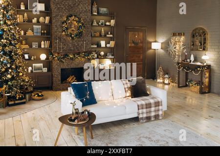 Festliches Wohnzimmer mit braunen Wänden mit weißem Sofa, blauen und braunen Kissen, Weihnachtsbaum mit Ornamenten und Lichtern, Steinkamin mit einem Stockfoto