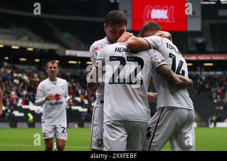 MK Dons-Stürmer Callum Henry (M) feiert das Treffer mit Laurence Maguire (L) und Joe Tomlinson (R) während des Spiels der Sky Bet League Two im Stadium MK Milton Keynes. Bilddatum: Samstag, 24. August 2024. Stockfoto